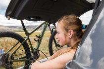 Дівчина-підліток сидить на багажнику позашляховика, дивлячись на Віста — стокове фото