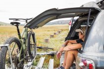 Donna adulta seduta sul portellone di un SUV guardando la vista — Foto stock