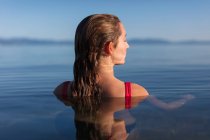 Ragazza adolescente, testa e spalle sopra l'acqua calmo lago all'alba — Foto stock