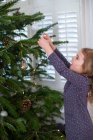 Young girl decorating Christmas tree with baubles. — Stock Photo