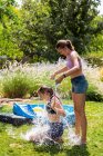 Дві дівчини-підлітки в купальнику грають з водними кульками в саду . — стокове фото