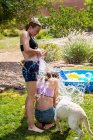 Two teenage girls wearing swimwear playing with water balloons in a garden. — Stock Photo