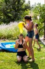 Dos adolescentes con traje de baño jugando con globos de agua en un jardín. - foto de stock