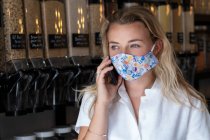 Portrait of young blond woman wearing face mask, standing in waste free wholefood store. — Stock Photo