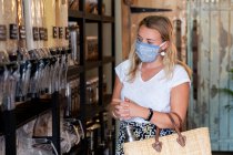 Женщина в маске для лица в магазине безотходных товаров — стоковое фото