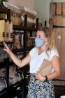 Жінка в масці для обличчя покупки, наповнюючи паперовий мішок вільними інгредієнтами — стокове фото