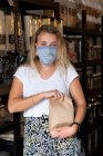 Donna che indossa maschera viso shopping riempiendo un sacchetto di carta con ingredienti sciolti — Foto stock