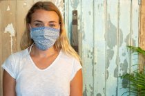 Portrait de jeune femme blonde portant un masque facial, debout dans un magasin d'aliments complets sans déchets. — Photo de stock