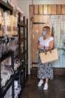 Mujer con mascarilla de compras en tienda local libre de residuos - foto de stock