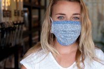 Portrait de jeune femme blonde portant un masque facial, debout dans un magasin d'aliments complets sans déchets. — Photo de stock