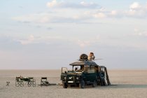 Mann steht auf Fahrzeug, das auf den Makadikadi-Salinen in Botswana geparkt ist. — Stockfoto