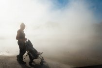 Donna e bambino in carrozzina in aumento vapore dalle piscine termali — Foto stock