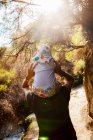 Mother giving her baby girl a piggyback ride on nature path by a thermal pool — Stock Photo