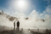 Dos personas en la niebla creciente en un sitio de piscina termal - foto de stock
