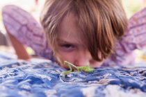Seven year old boy looking at a praying mantis — Stock Photo