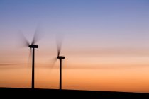 Two wind turbines turning, sunset sky — Stock Photo