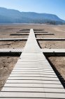 Plancas dispuestas como pasarelas, muelles sobre tierra plana seca del desierto, espacio abierto. - foto de stock