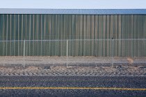 Corrugated iron building with a fence, by highway — Stock Photo