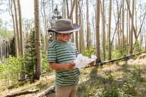 Seven year old boy holding treasure map in forest of Aspen trees — стоковое фото