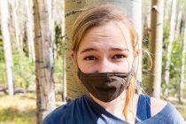 Ragazza adolescente che indossa maschera COVID-19 nella foresta di alberi di Aspen — Foto stock