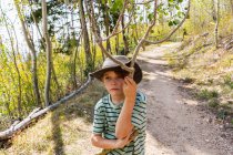 Seven year old boy holding broken branch in forest of Aspen trees — Stock Photo