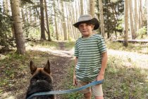 Menino de sete anos andando seu cão na floresta de árvores de Aspen — Fotografia de Stock