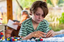 Garçon de sept ans jouant avec des blocs de construction sur une terrasse — Photo de stock