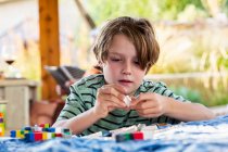 Seven year old boy playing with building blocks on a terrace — Stock Photo