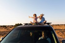 Дівчинка-підліток і її молодший брат на вершині позашляховика водіння на пустельній дорозі — стокове фото