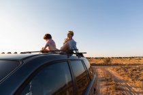 Дівчинка-підліток і її молодший брат на вершині позашляховика водіння на пустельній дорозі — стокове фото