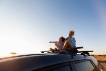 Adolescente e seu irmão mais novo no topo do carro SUV na estrada do deserto, Galisteo Basin, Santa Fe, NM. — Fotografia de Stock