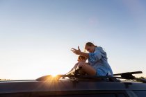 Adolescente et son frère cadet au sommet de la voiture SUV sur la route déserte, bassin de Galisteo, Santa Fe, NM. — Photo de stock