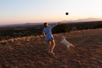 Дівчина-підліток кидає футбол на заході сонця . — стокове фото