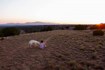 Junge sitzt mit Hund auf Feld. — Stockfoto