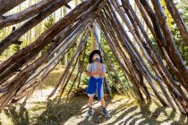 Jeune garçon levant les yeux, debout dans un tunnel en rondins d'arbre. — Photo de stock