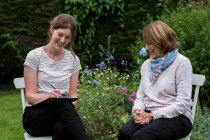 Mulher e terapeuta feminina em uma sessão de terapia alternativa em um jardim. — Fotografia de Stock