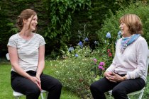 Donna e terapista donna sedute a una sessione di terapia alternativa in un giardino. — Foto stock