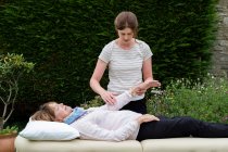 Terapeuta Reiki com um cliente em uma sessão de terapia tocando pontos meridianos no corpo. — Fotografia de Stock