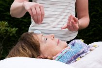 Terapeuta reiki con un cliente in una sessione di terapia che tocca punti meridiani sul corpo. — Foto stock