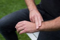 A man sitting, two fingers on his opposite wrist, EFT touching therapy — Stock Photo