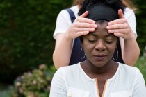 Therapist with her hands on a client temples, outdoor therapy session — Stock Photo