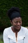 Портрет черной женщины, сидящей в саду, улыбающейся во время сеанса альтернативной терапии. — стоковое фото