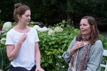 Terapista e cliente seduti in giardino, donne con le mani sul petto — Foto stock