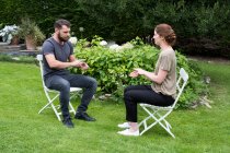 Hombre y mujer terapeuta que participan en una sesión de terapia alternativa en un jardín. - foto de stock