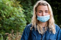Portrait of young blond woman wearing face mask, looking at camera. — Stock Photo