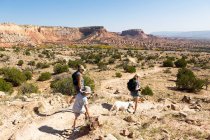 Três pessoas, caminhadas em família em um trilho através de uma paisagem canyon protegida — Fotografia de Stock