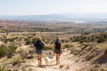 Tres personas, caminatas familiares en un sendero a través de un paisaje protegido del cañón - foto de stock
