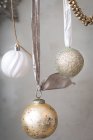 Рождественские украшения, серебряные, белые и золотые безделушки на лентах на сером фоне. — стоковое фото