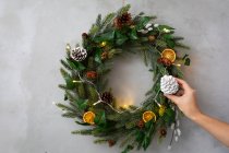 Addobbi natalizi, primo piano della persona che decora la corona natalizia con ornamenti. — Foto stock