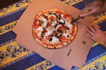 Високий кут крупним планом людини, що ріже піцу з піцерійним колесом . — стокове фото